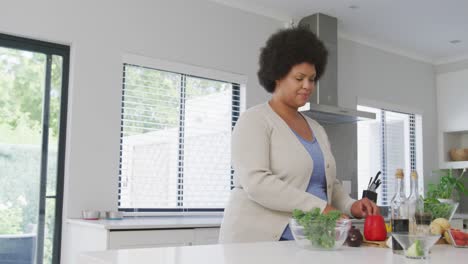 Video-of-plus-size-african-american-woman-using-tablet,-preparing-meal