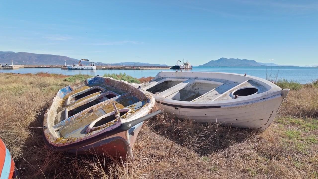 Barche da pesca greche abbandonate e trascurate su una spiaggia erbosa in disuso