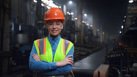 Woman-mechanic-crossing-hands-looking-camera-at-manufacturing-special-facility.