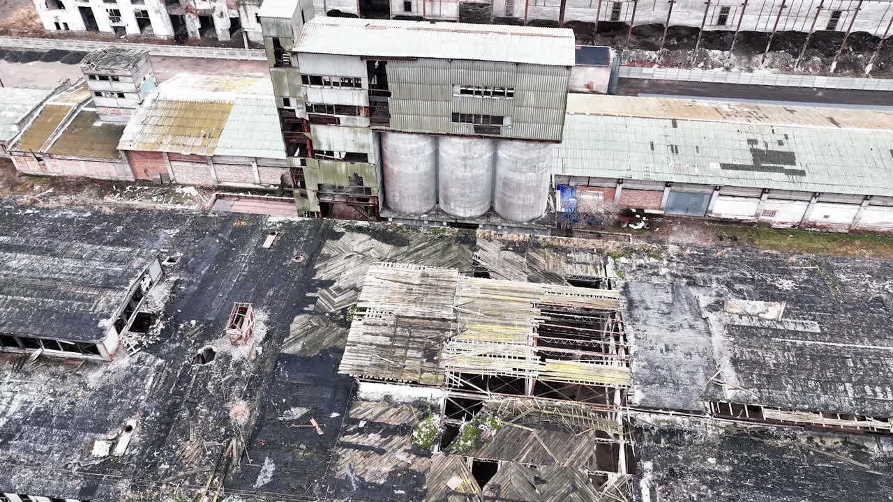Warehouses of an old plant. Aerial perspective on the wrecked roof of a long empty warehouse in the industrial area.