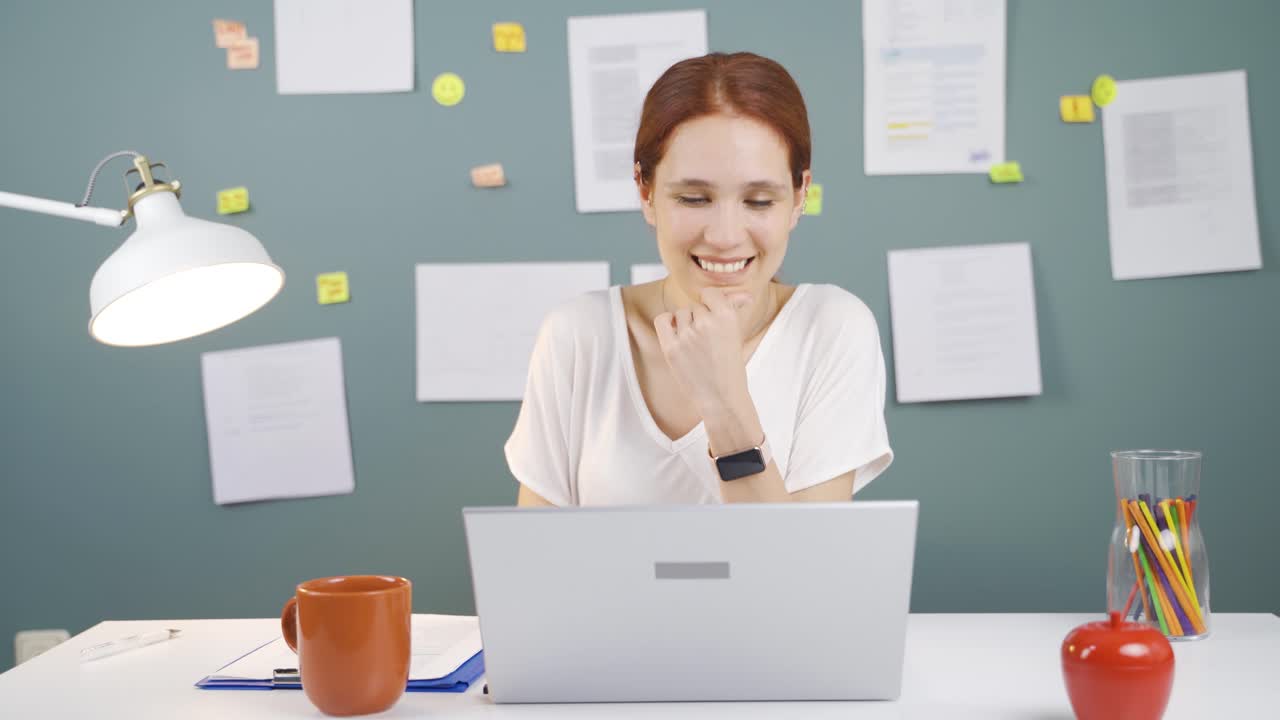 Woman working on laptop with happy expression.