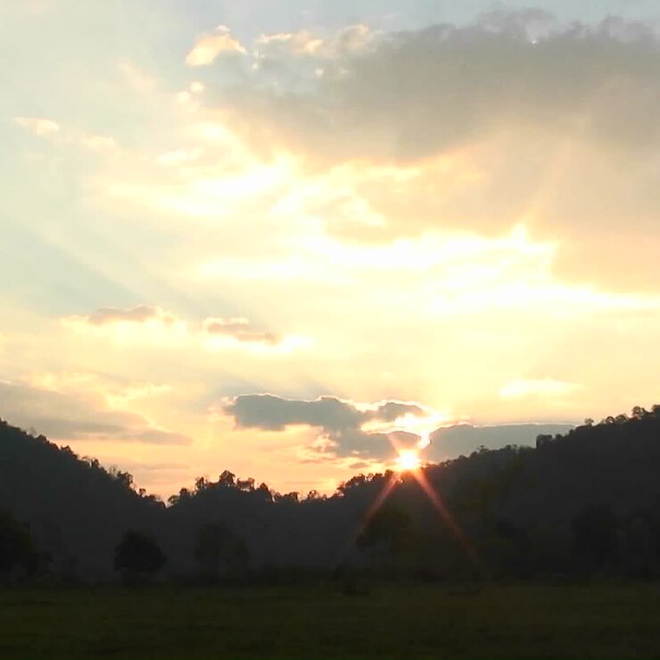 El sol sale sobre montañas y una masa de agua.