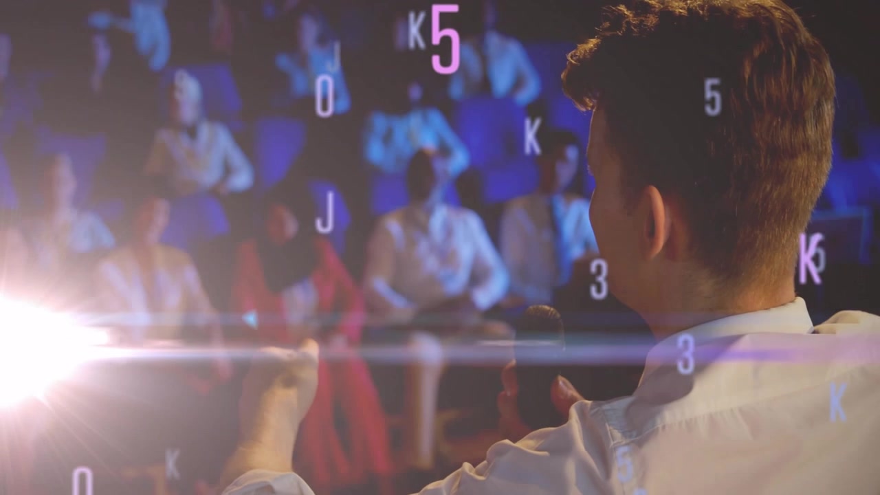 Presenter gesturing and speaking onstage activating floating alphanumeric graphics showing data