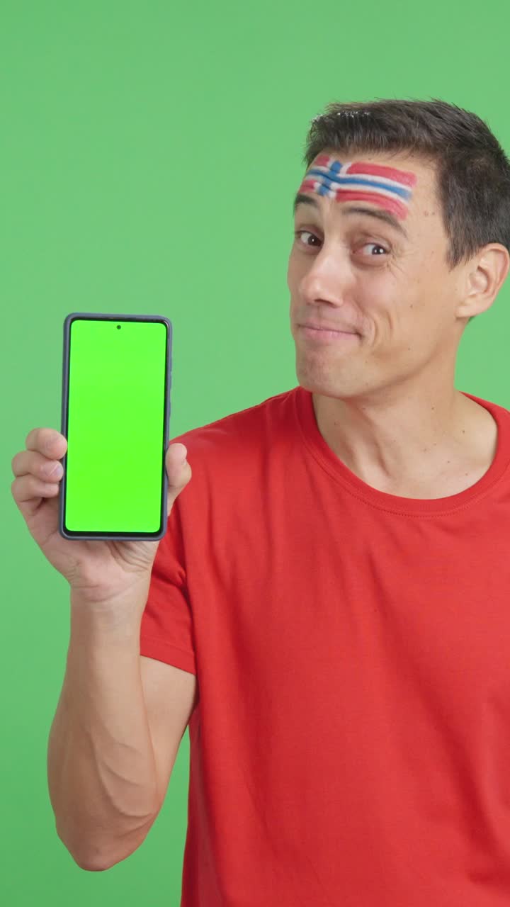 Norwegian supporter looking at his mobile smiling and showing it