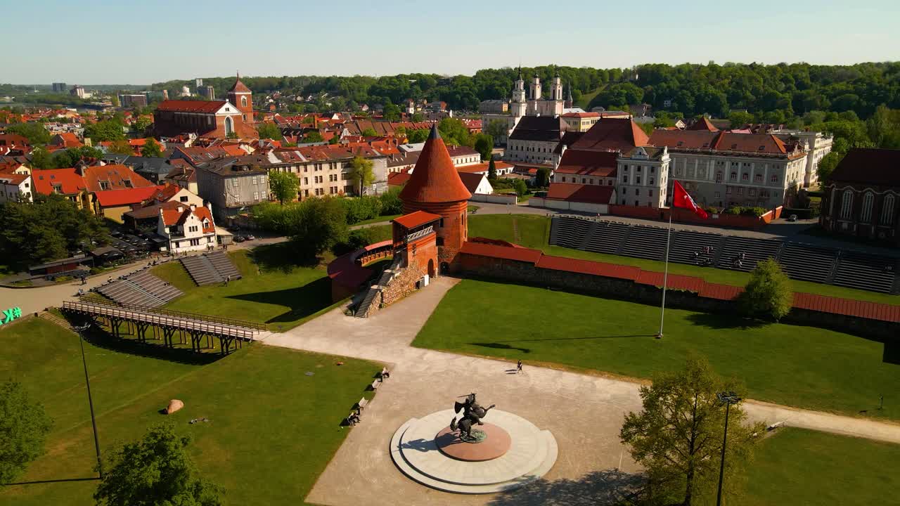 tomada de avión no tripulado del histórico castillo de ladrillo rojo de kaunas con la estatua de vytis en el casco antiguo de kaunas, lituania en un día soleado, toma de paralaje