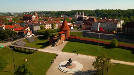 drone shot of the historic old red brick kaunas castle with vytis statue in kaunas old town, lithuania on a sunny day, parallax shot