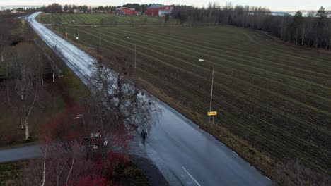 Man-Skiing-Down-Wet-Street-In-The-Evening-Near-Ostersund,-Sweden