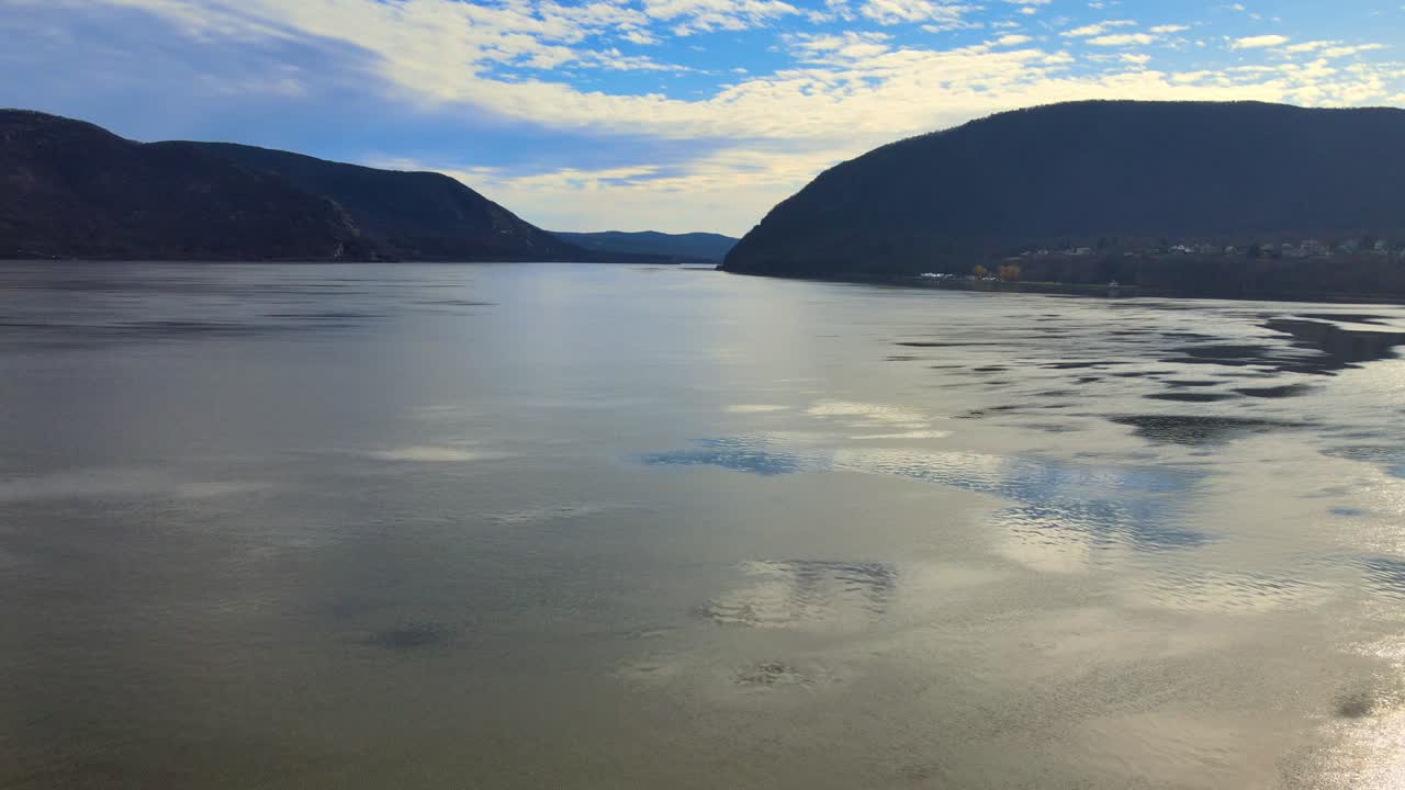 드론이 물을 가로질러 경주한 다음 가을의 화창한 날에 강 계곡 위로 빠르게 상승합니다.