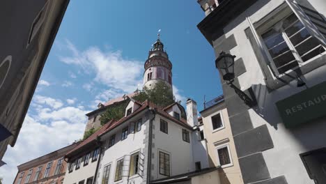 vista general en ángulo bajo de la torre del castillo en český krumlov, chequia, enmarcada contra un cielo despejado y arquitectura histórica