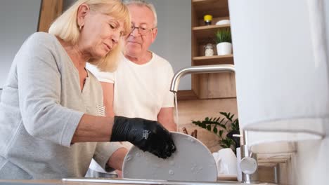elderly couple washing dishes in the kitchen