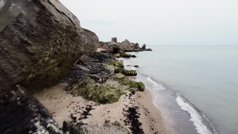 aerial view of abandoned seaside fortification building at karosta northern forts on the beach of baltic sea in liepaja in overcast spring day, wide drone shot moving forward low close to the building