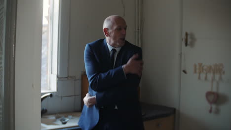 a confused mature senior businessman is shivering in a dark kitchen in winter