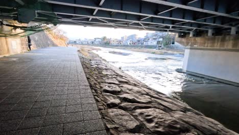 pathway under bridge along kyoto riverbank