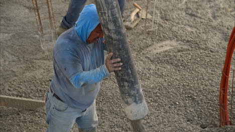 close up de un trabajador de la construcción latino mexicano con una capucha aplicando hormigón fresco con una bomba de boom en cámara lenta