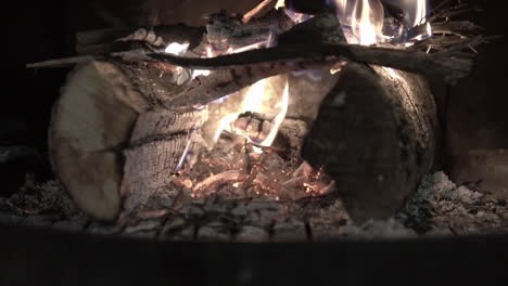 clip de cámara lenta de un primer plano de un fuego de madera ardiendo dentro de una chimenea negra rural tradicional en una casa de invierno