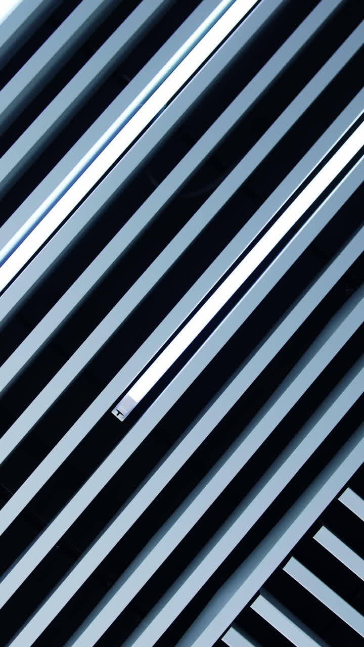 Unusual design of the ceiling in the room. Decorative planks with lamps of daylight among them. Low angle view. Vertical video