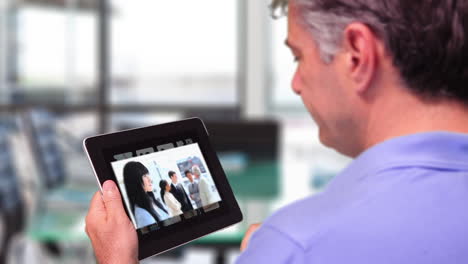 man using tablet to view business people at work