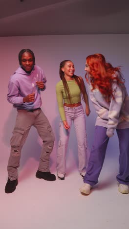 vertical video studio shot of vertical video of group of gen z friends dancing and having fun against pink background 1