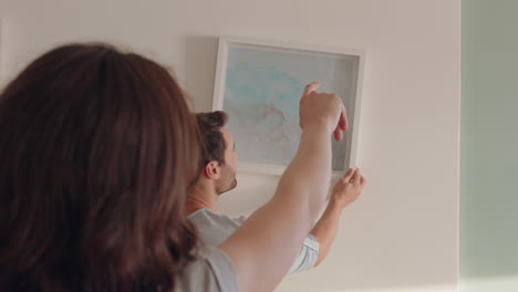 young couple moving into new home owners hanging picture decorating house together enjoying teamwork high five in apartment