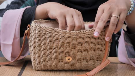 woman putting her phone in her straw bag