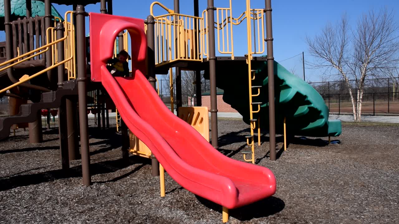 niño disfrazado de dinosaurio se desliza por el tobogán