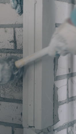 professional man hand fixes gypsum plasterboard lines on wall holding special rubber hammer close view