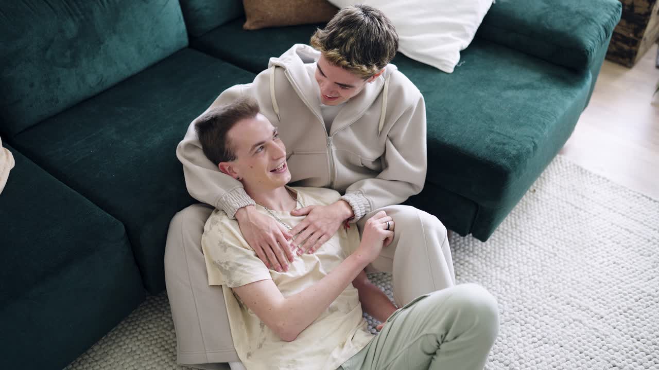 Happy Young Gay Couple Talking and Embracing at Home