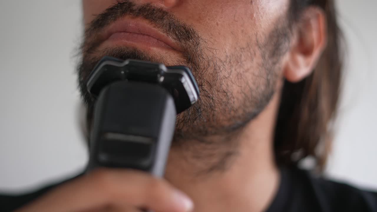Latino muž zastřihující si vousy a knír elektrickým holicím strojkem, Holení