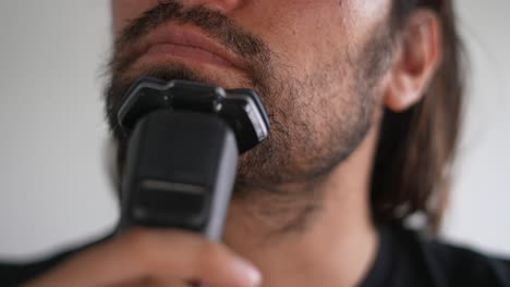 hombre latino recortando barba y bigote con afeitadora eléctrica, afeitarse