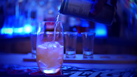 an energy drink is poured from a can into a glass filled with ice