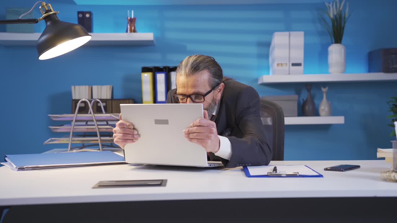 노트북에서 일하는 성숙한 비즈니스맨이 기 ⁇ 하고 에너지로 미소를 짓고 있습니다.