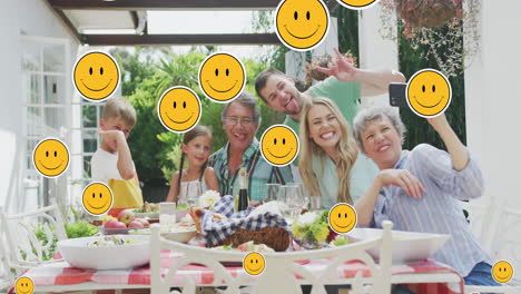 animation of smiley faces over happy caucasian family taking selfie in garden