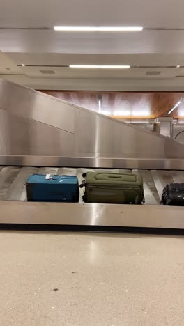 airport conveyor belt or luggage carousal with different suitcases and bags. terminal with landing flights check in bags arriving. phone camera pov user generated style content from amateur traveler