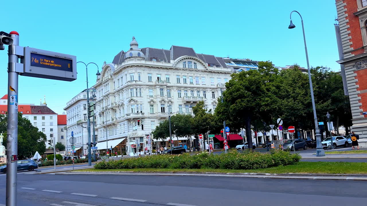 Vienna, Austria - June 9, 2025: Road signs along with the names of the street on the pavement. View on the big beautiful white old-fashioned building across the street. Vienna, Austria
