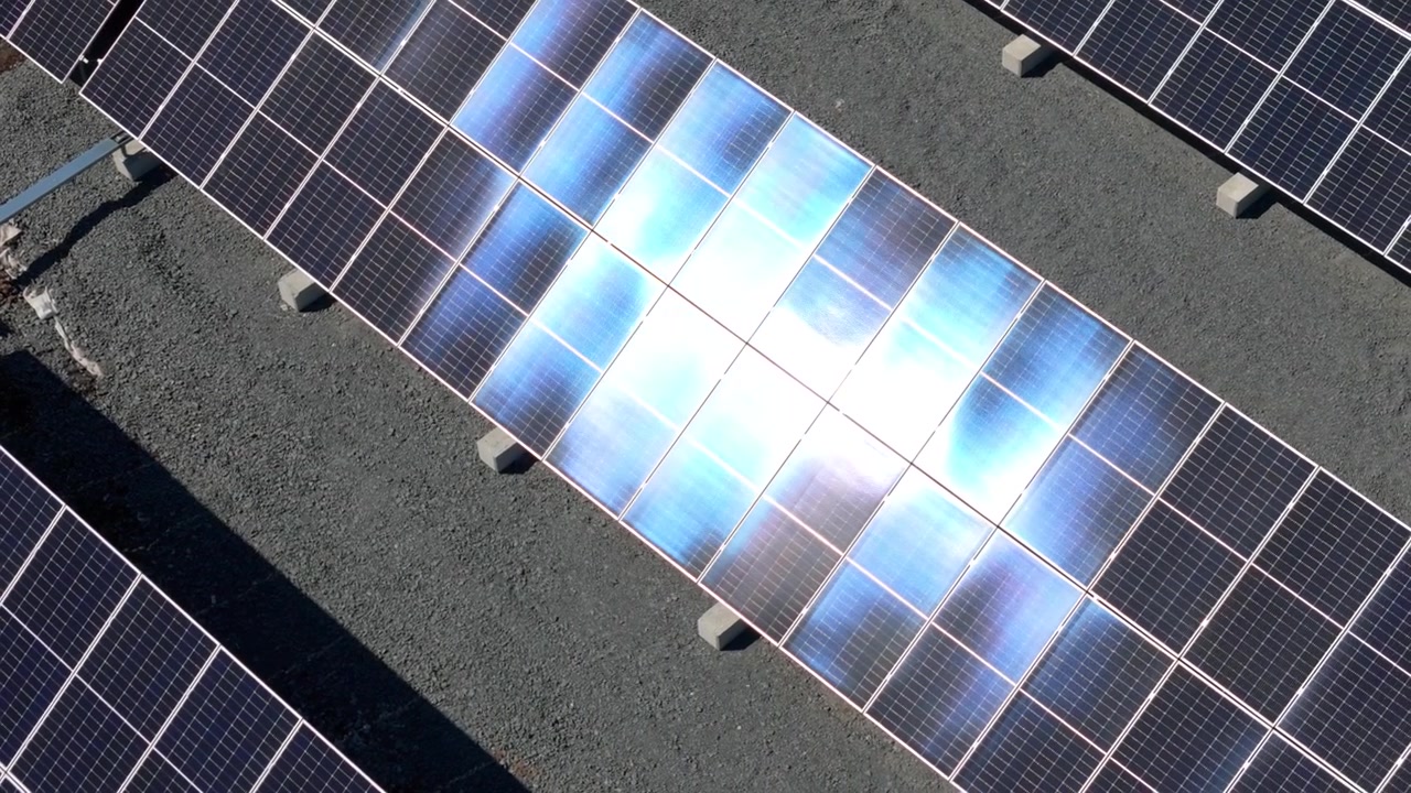 Orbita aerea ravvicinata di pannelli solari in un parco energetico, che riflettono la luce solare scintillante.