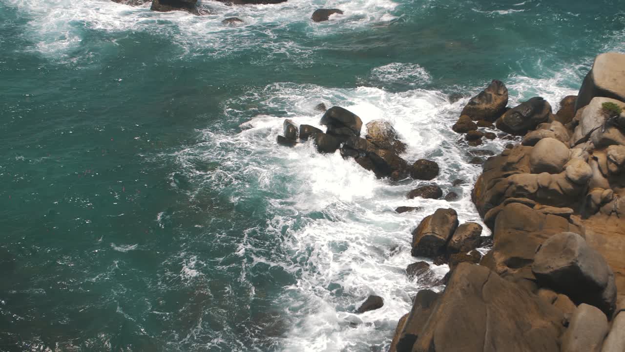 Onde schiumose che si infrangono contro le rocce al rallentatore nel Parco Tayrona, Colombia.