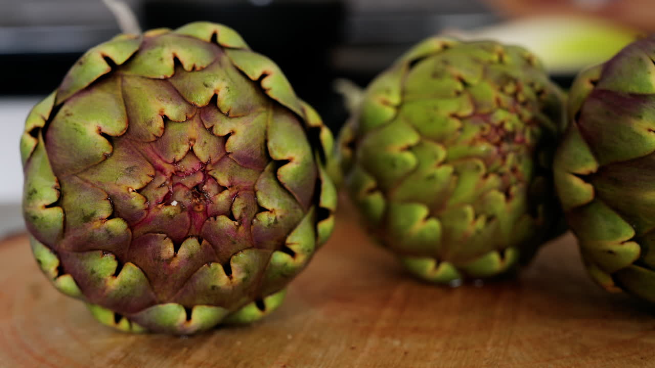 Close up of three artichokes on a wooden table