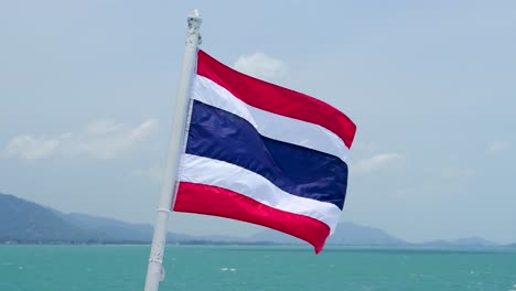 thai flag waving in wind from back of boat on open ocean