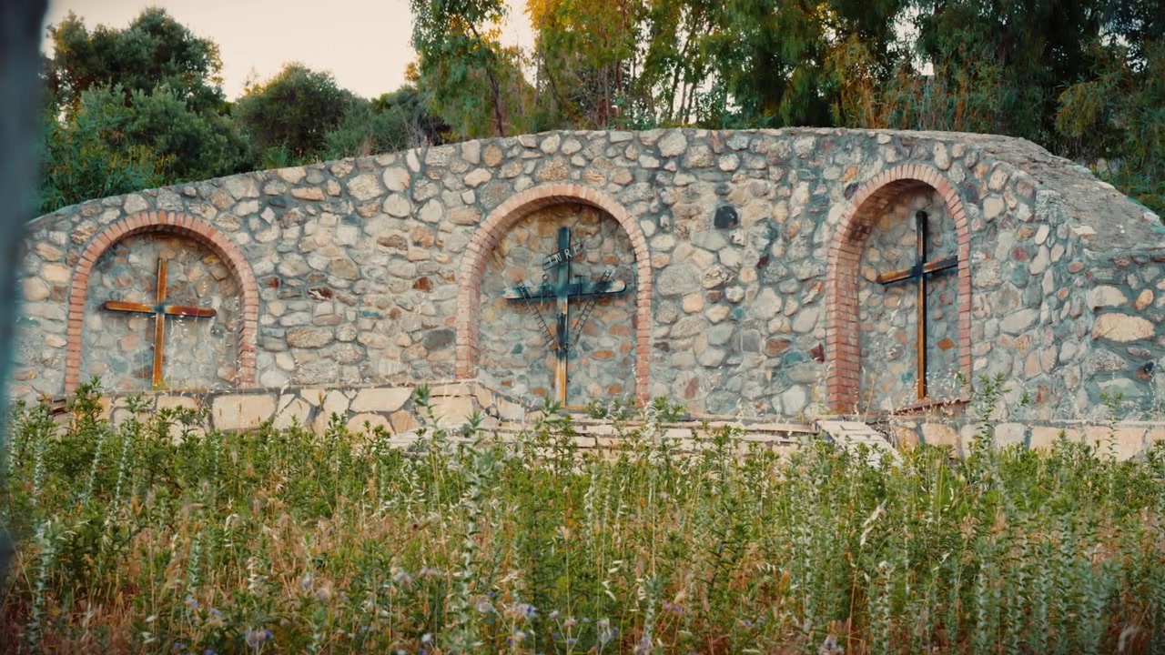 Scena religiosa del Calvario con tre crocifissi al tramonto in un sereno paesaggio naturale
