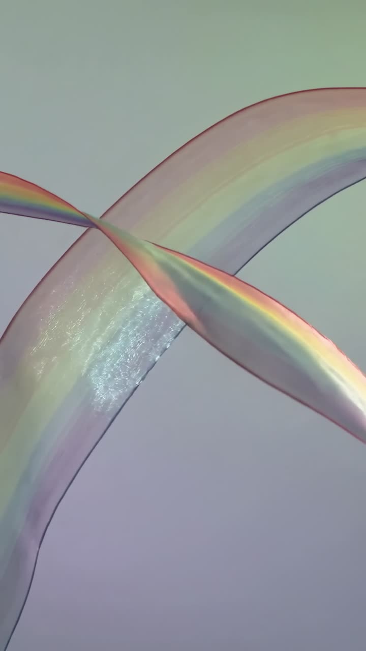 Vertical video: Breeze pushing two iridescent soap ribbons crossing center backdrop, creating X