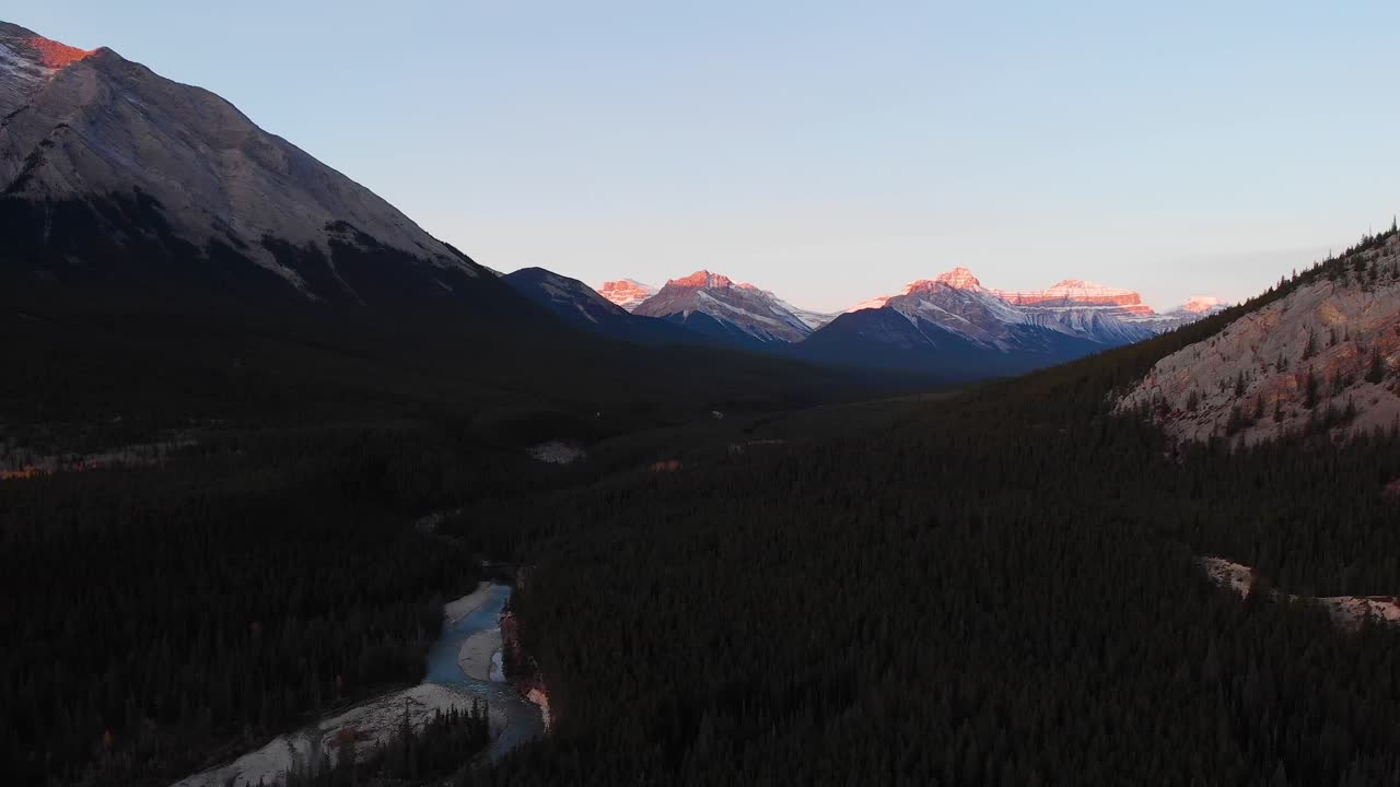 picos nevados de las montañas rocosas canadienses al atardecer por avión no tripulado