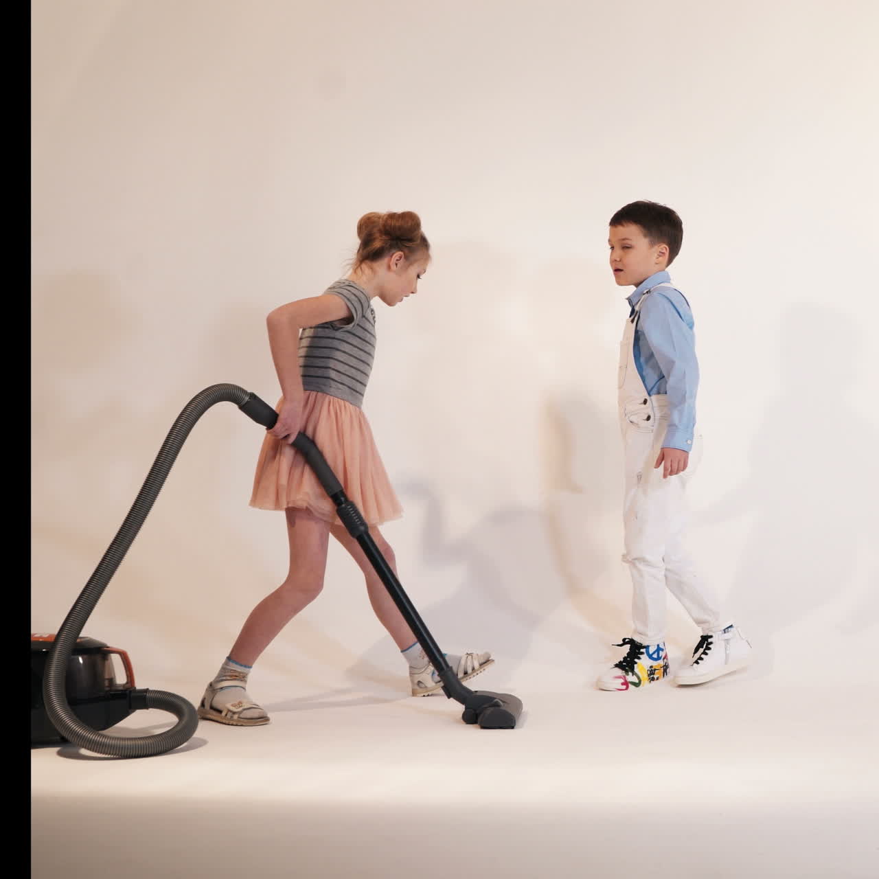 Little children play with a vacuum cleaner. Emotions of the child. Studio shooting of children.