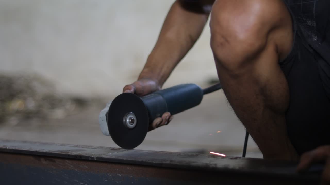 노동자 들 은 수동 가루 를 사용 하여 철 을 자르고 있다. 가루 에서 어지는 불꽃 이 곳곳 에 어지고 있다