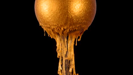 la pintura de brillo dorado fluye lentamente de la pelota