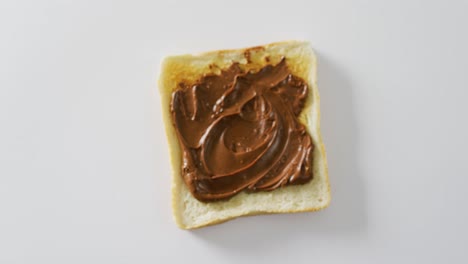 Video-of-close-up-of-toast-with-chocolate-cream-on-white-background