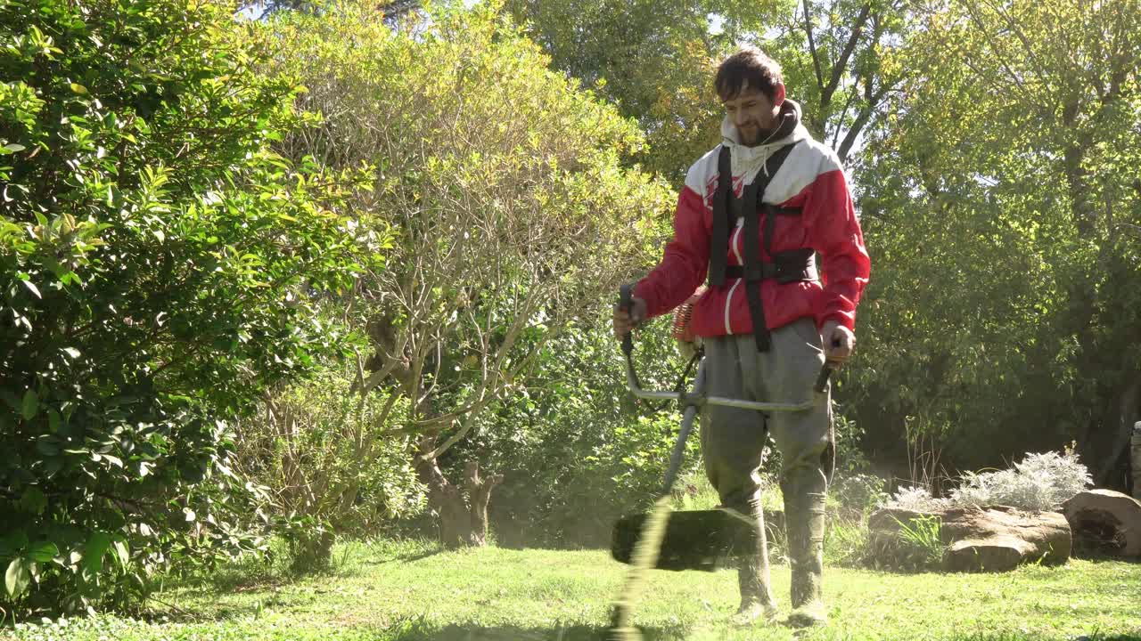 Landscaper cutting overgrown grass using a powerful gasoline string trimmer in a residential yard