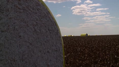 cotton bales in protective wrap at cotton field, pull back drone shot