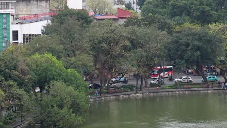 traffic and pedestrians near a lakeside in hanoi