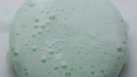water reacting with an effervescent tablet, creating fizzing effect with bubbles and foamy surface. closeup, overhead shot