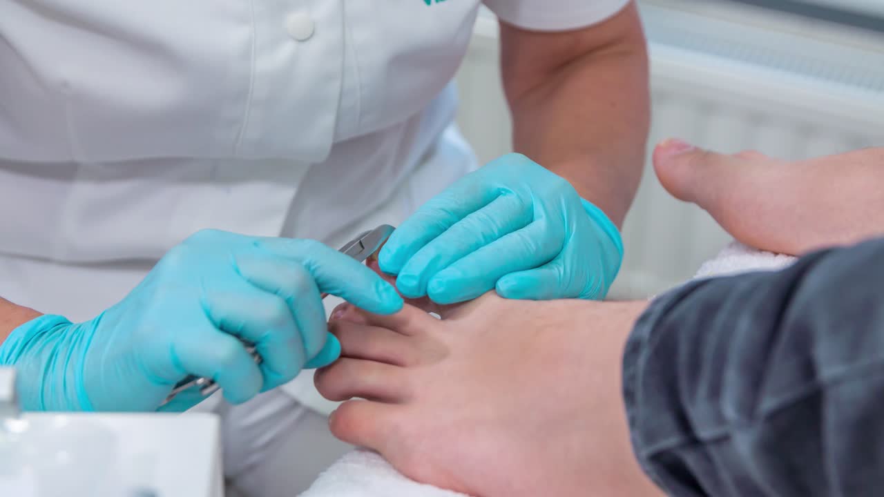 Una esteticista está cortando las uñas de los pies de su clienta y le está haciendo un masaje completo y una pedicura en un estudio de masajes.